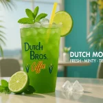 Dutch Mojito iced beverage from Dutch Bros. Coffee in a cup with a lime slice and mint, set on a table with a tropical background