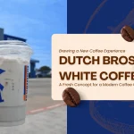 image for Dutch Bros White Coffee, showing a hand holding a white coffee cup with the blue windmill logo in front of a Dutch Bros drive-thru, alongside text "Brewing a New Coffee Experience - Dutch Bros White Coffee" and coffee beans.